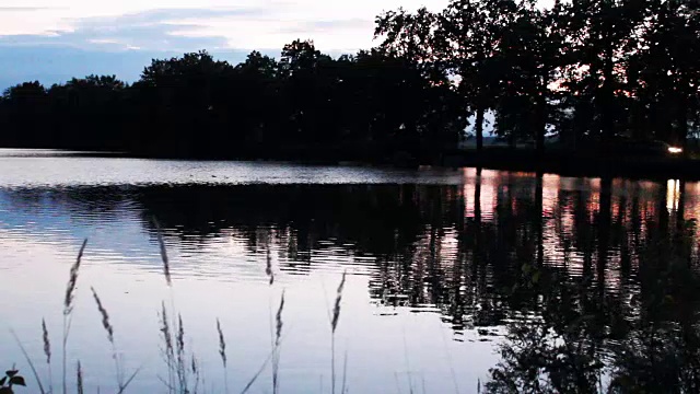 日落时分，汽车在池塘大坝上行驶视频素材