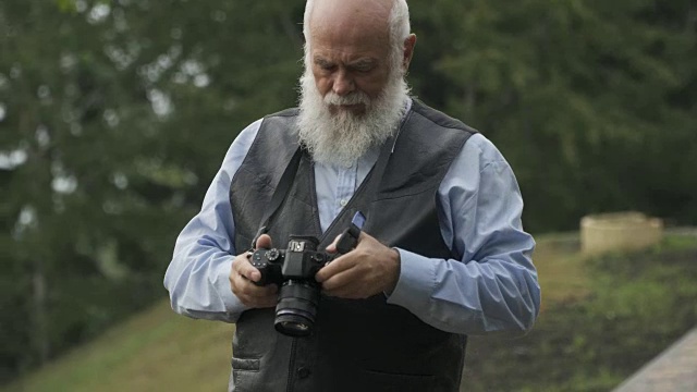 一位白发苍苍的老人正在拍摄秋天的公园视频素材