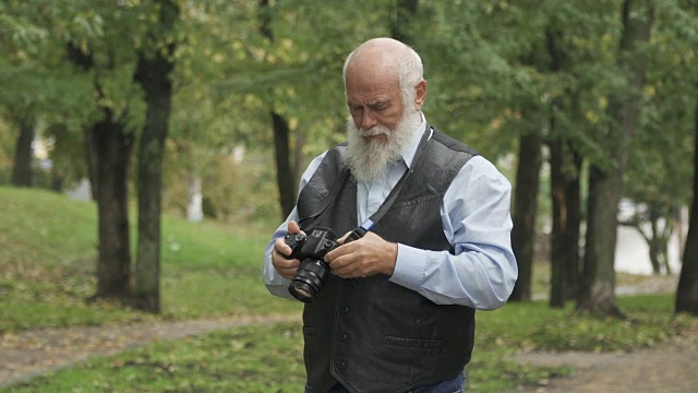 一位老人在公园里拍大自然的照片视频素材