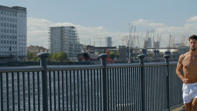 一个非常健康的年轻人赤膊跑过伦敦，英格兰码头区。视频素材