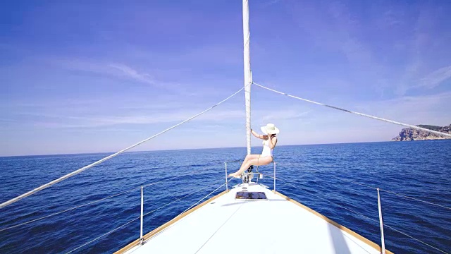 穿着泳衣的女人坐在帆船的船头上视频素材