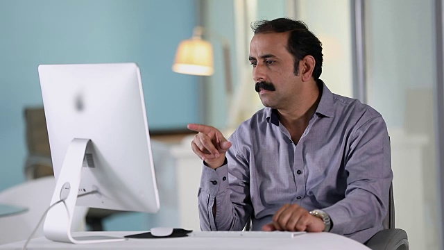印度德里，一名成年男子在办公室的台式电脑上工作视频素材