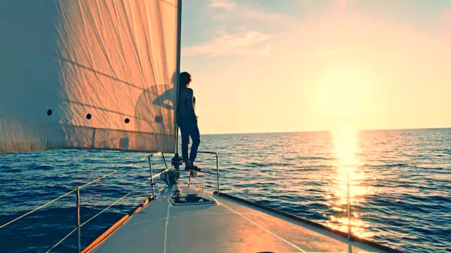 一个女人在帆船的船头欣赏日落视频素材