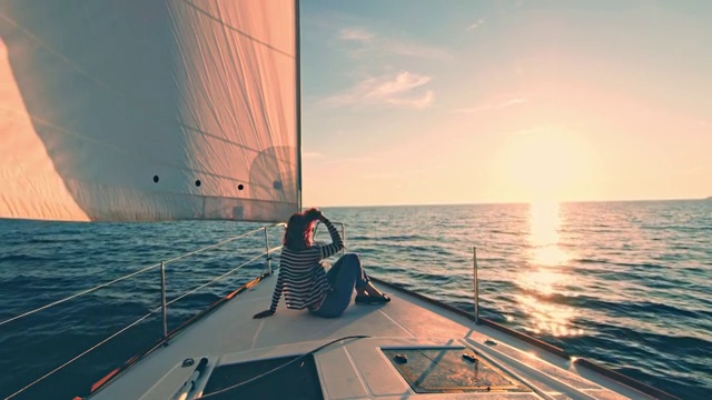 一个女人在一艘帆船的甲板上欣赏日落视频购买