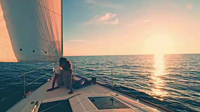 日落时分，一对夫妇在一艘帆船的甲板上休息视频素材