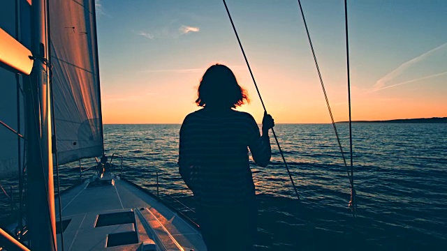一个女人在帆船的甲板上欣赏日落视频素材