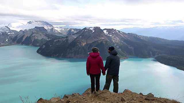 一对夫妇站在山顶上欣赏风景视频素材