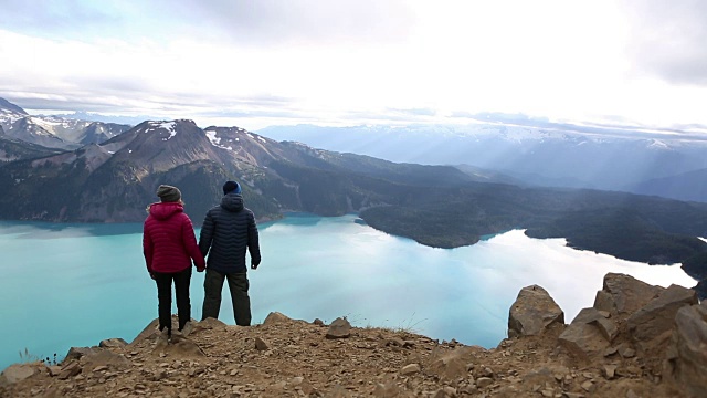 一对年轻夫妇站在山顶上看风景视频素材