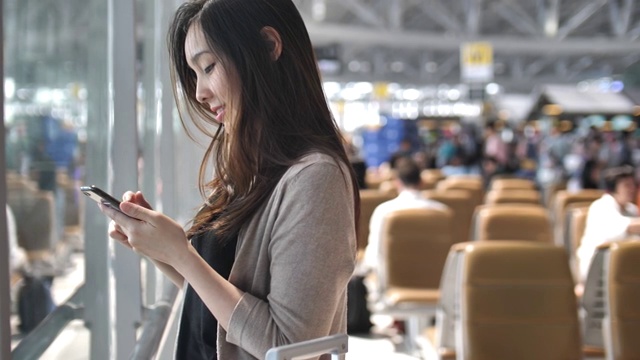 一名女子在机场使用智能手机视频下载
