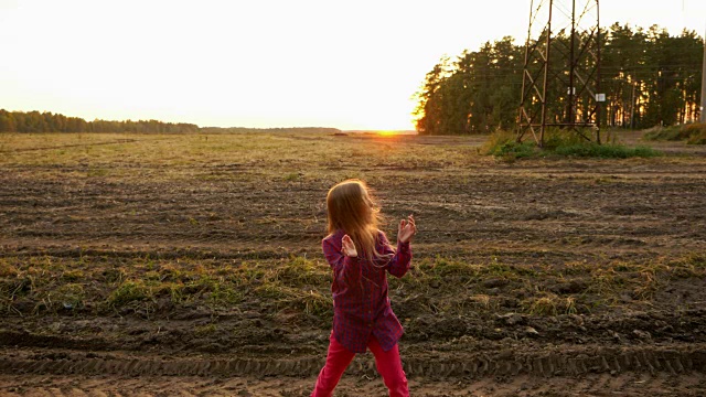 年轻的白人女孩拍手在日落的乡村景色。美丽的女孩一边跳舞一边四处张望。视频下载