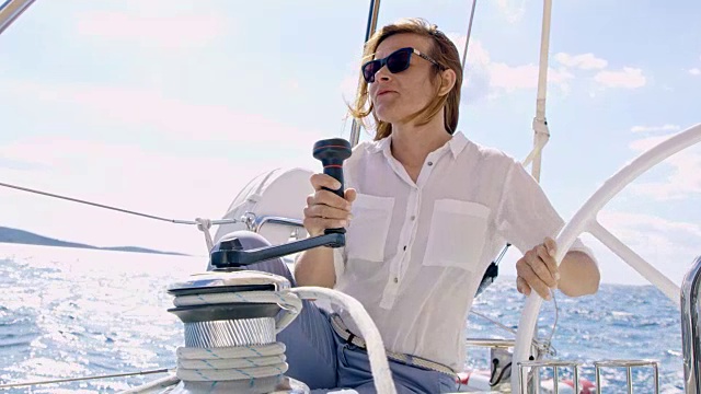 女子在驾驶帆船时转动绞车视频素材
