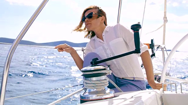 一名妇女在驾驶帆船时将绳子系在绞车上视频素材