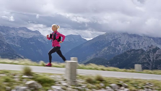 SLO MO TS女运动员在阳光下的高山路上奔跑视频素材