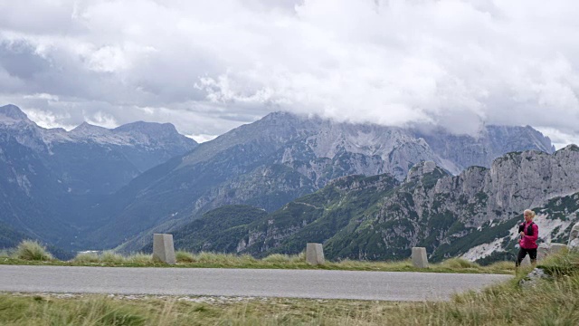 女人在高山上的公路上奔跑，有美丽的风景视频素材