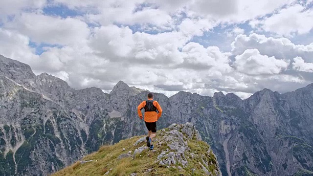 SLO MO男运动员在一个山脊的边缘上跑步，有着令人惊叹的景色视频素材