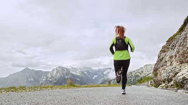 一个女人在高山上的柏油路上奔跑视频素材