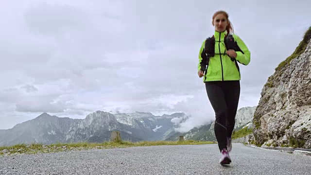 女运动员在一个阴天的高山路上跑上山视频素材