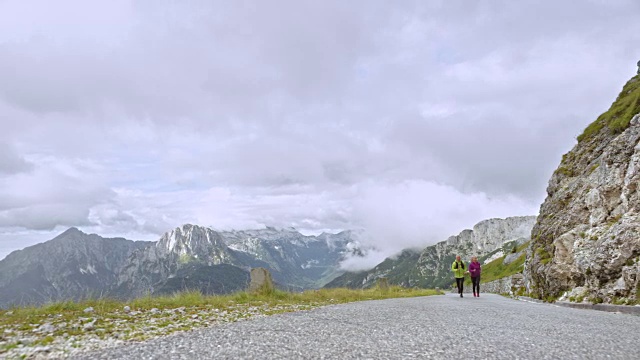 老男人和老女人跑上一条高高的山路，俯瞰着附近的群山视频素材