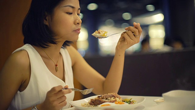 年轻的亚洲女士在咖啡馆吃泰国菜视频素材