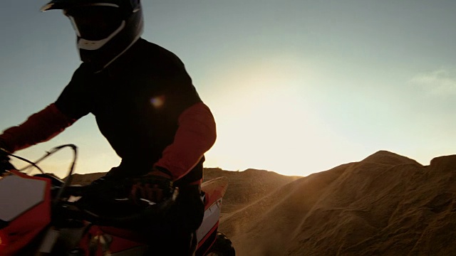 专业摩托车越野赛摩托车骑手在沙丘和越野车道上行驶。这是《日落》，赛道上布满了烟雾。视频素材