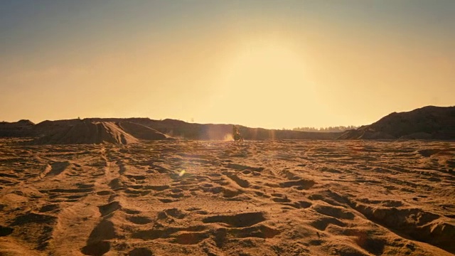 以下是职业摩托车越野赛摩托车骑手在风景优美的采石场中间的土路越野赛道上驾驶的照片，而太阳正在下山。视频素材