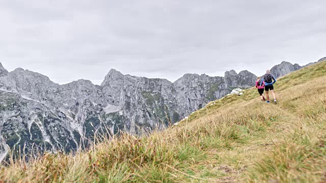 一对夫妇在高山上长满草的山脊上跑步视频素材