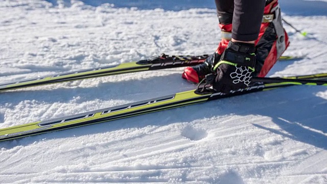 越野滑雪者走到他的滑雪板上，把它们绑好视频素材