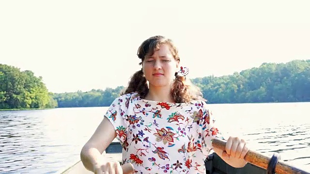 认真专注专注的年轻女子在弗吉尼亚的湖面上划着船，在温暖，柔和的阳光下，阳光，阳光视频下载