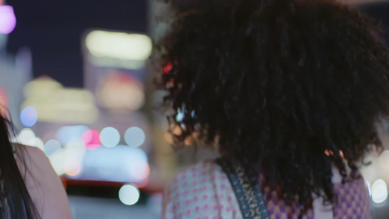 SLO MO.年轻女子转身对着镜头微笑，晚上手牵手走在拉斯维加斯大道上。视频素材