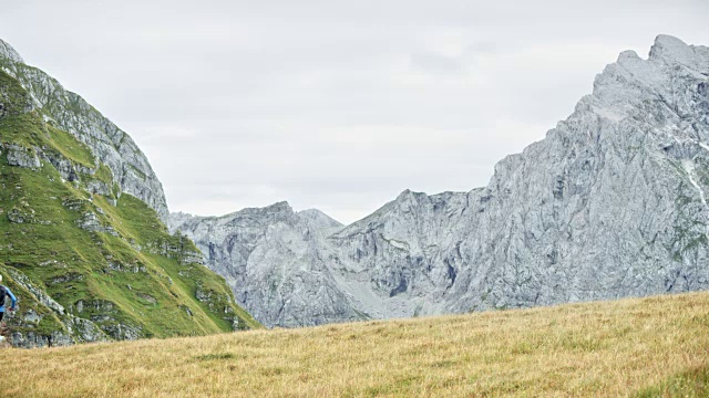 男男女女从山上的草地上跑下来，俯瞰附近的山峰视频素材