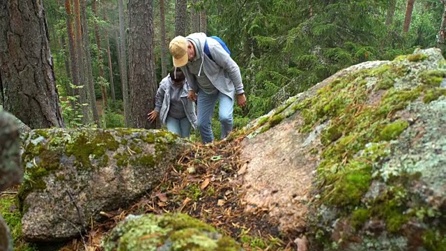 一对活跃的老年夫妇在北部森林的岩石上攀岩视频购买