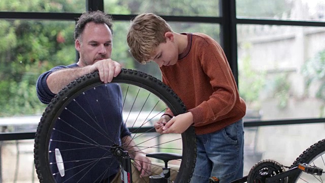 父亲教儿子如何给自行车轮胎打气视频素材