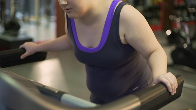 不健康的超重妇女因在跑步机上锻炼，行走缓慢而疲惫不堪视频素材