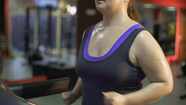 强壮的超重女性努力减肥，在跑步机上出汗视频素材