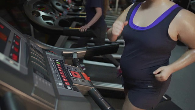 流汗的超重女人在跑步机上跑步，减肥运动和节食视频素材