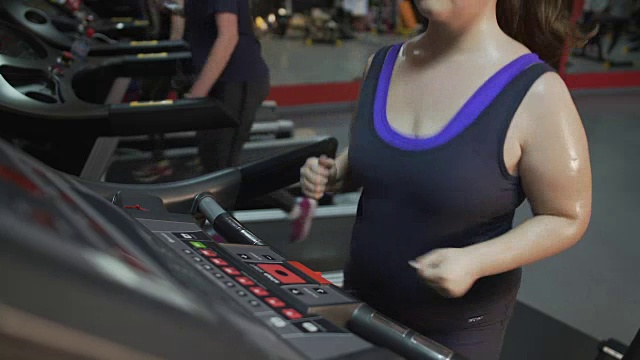 体重超标的女性在跑步机上快速奔跑，努力保持苗条的身材视频素材