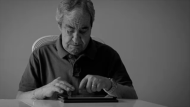 70岁的老人在家用平板电脑用单色输入电子邮件。视频素材