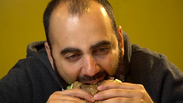 一个留着胡子的男人正在吃一个多汁的肉汉堡视频下载