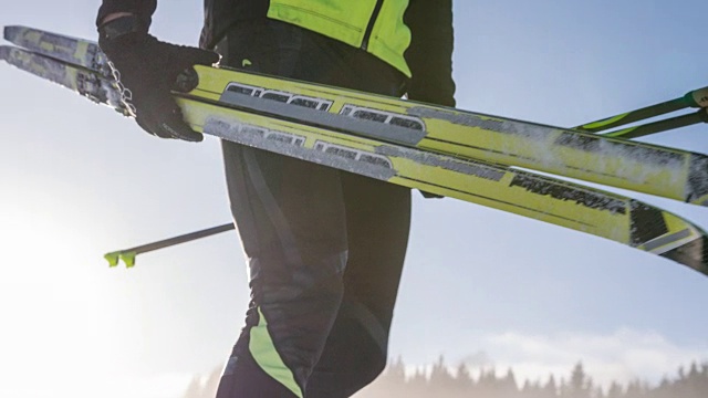 越野滑雪者在冬季景观携带他的运动设备视频素材