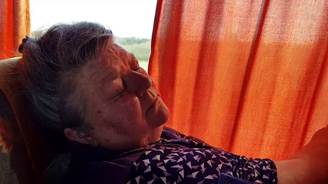 在长途旅行中，一位老妇人睡在车窗旁的公交车上。视频素材