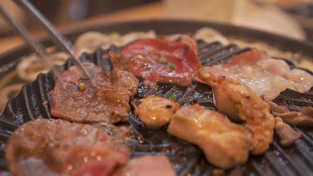 烹饪烧烤，在炉子上的木炭上烤。关闭牛肉烤在日本餐厅。用于烧烤或日式食物的生牛肉片视频购买