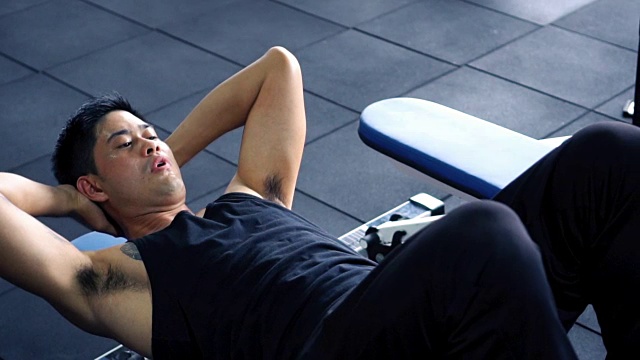 男人在长凳上做仰卧起坐，锻炼他的腹肌视频素材