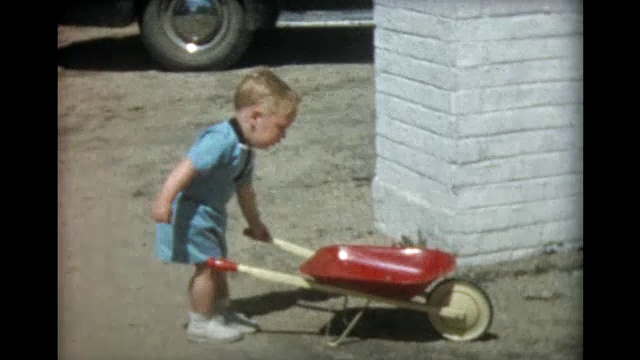 1957年，一个两岁的男孩开着红色的手推车视频素材