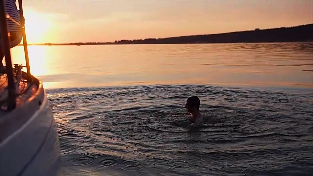 日落时分，一名男子从游艇上跳入河中视频下载