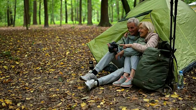 一对快乐的老游客夫妇在树林里使用他们的照相机视频下载