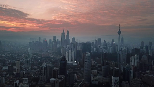 燃烧的天空映衬着吉隆坡摩天大楼与雾和薄雾的早晨。视频素材