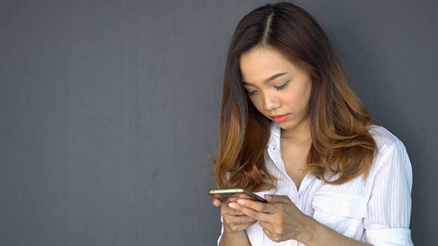 年轻的亚洲女人用她的智能手机玩和打字视频素材