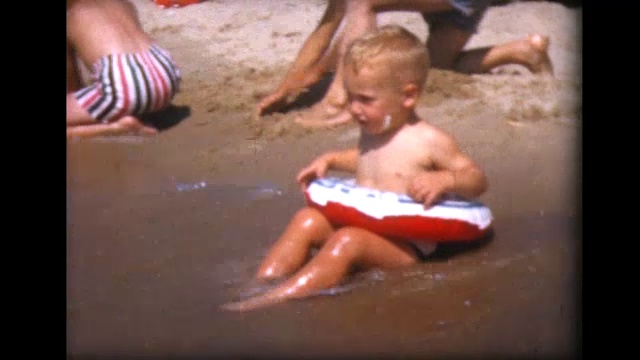 1957年，一名两岁男孩在内胎里在海里溅起水花视频素材