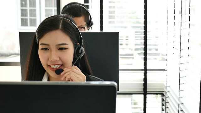 男性和女性呼叫中心工作人员戴着耳机视频素材