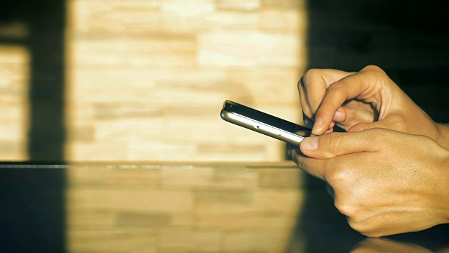 一个年轻女孩使用智能手机的手的特写照片坐在厨房的桌子旁。视频素材